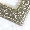A large, reverse curve profile frame with an intricate leaf design bordered by a geometric outer edge and beaded inner lip. A dark, matte Gold brown base with gold foil patina for added depth on the topmost points of the design. Strong, solid wood construction.
3.25 " witdth: ideal for large and oversize (extra large) images.